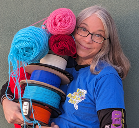 Vicky Somma looking flustered holding filament spools and yarn